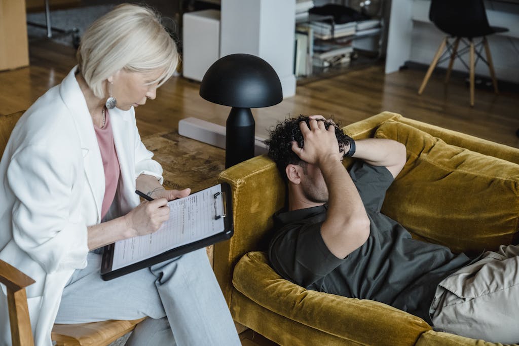 A therapist conducts a session with a client discussing mental health in a cozy office setting.