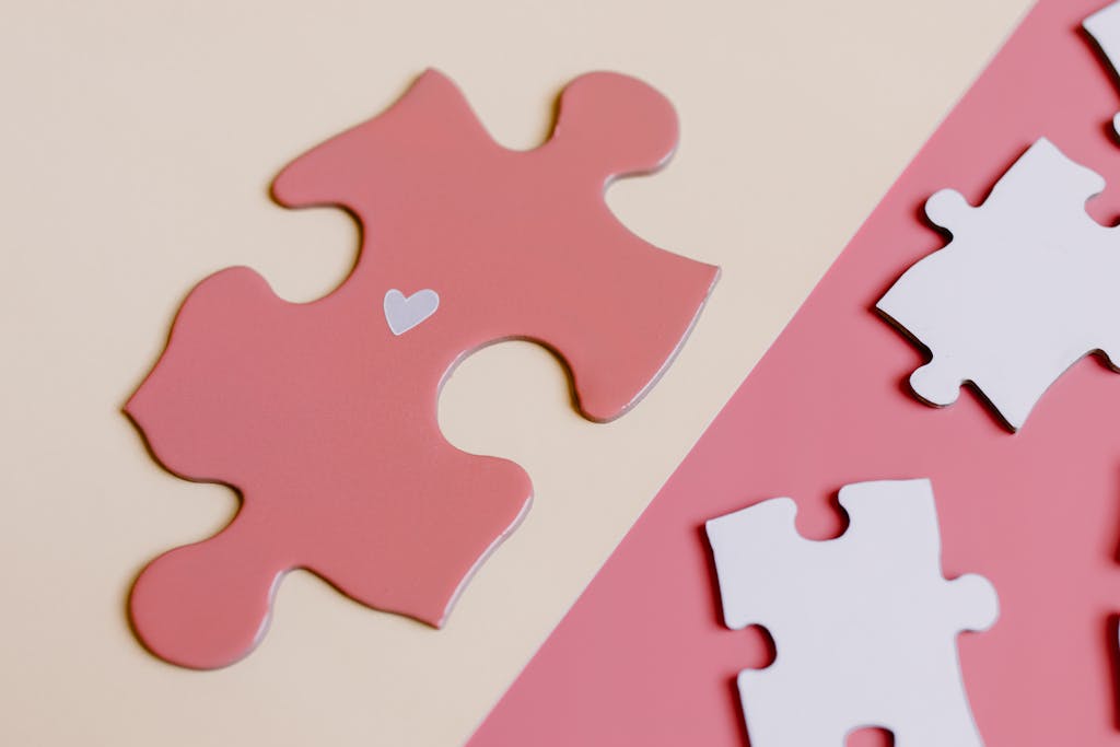 Close-up of a pink jigsaw puzzle piece with a heart, representing the concept of unity and connection.
